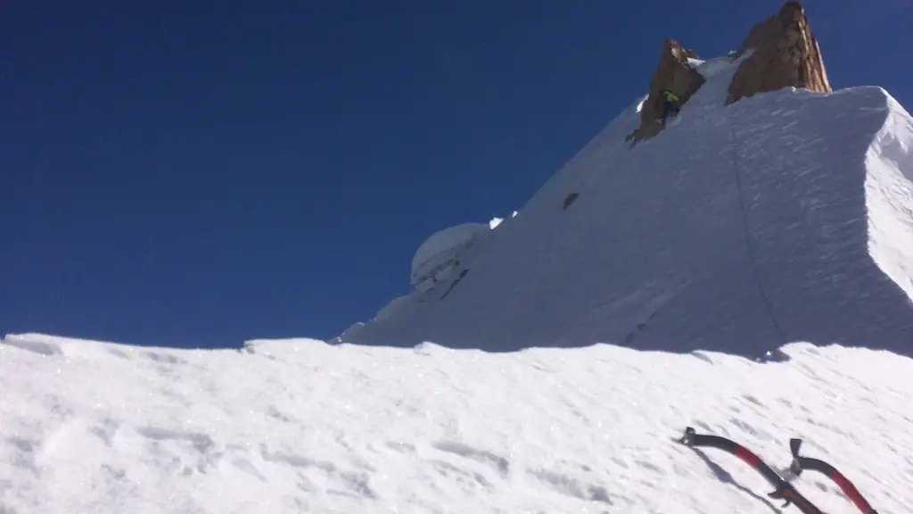 Two ice axes in the snow below a rock tower on a corniced ridge